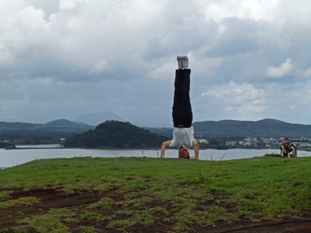 Mann macht Kopfstand auf dem Gras auf der Insel Jeju. Südkorea