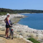 Junge Frau mit Fahrrad an der Küste des Nationalparks Brijuni, Kroatien