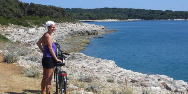 Junge Frau mit Fahrrad an der Küste des Nationalparks Brijuni, Kroatien