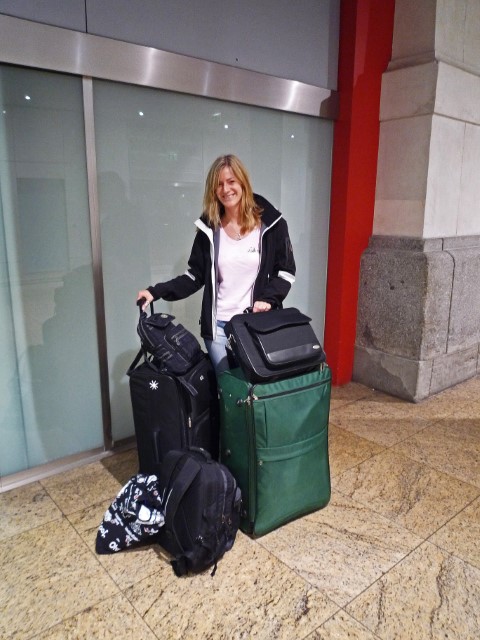 Junge Frau mit viel Gepäck am Bahnhof