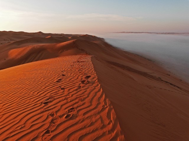 Sonnenlicht auf einer Wüsten-Düne, darunter Nebel