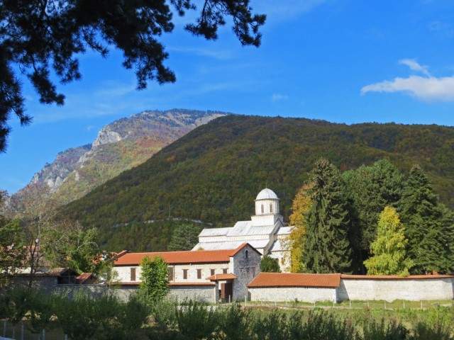 Blick auf das weiße Kloster Dečani vor grünen Bergen