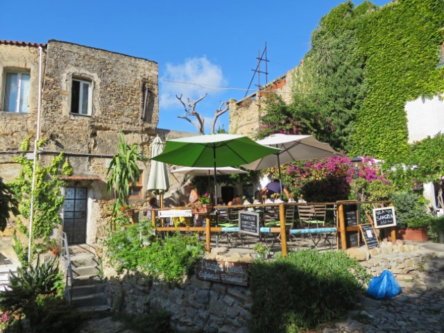Gemütliches Café zwischen alten Steinhäusern und neben einer Efeu-begrünten Mauer